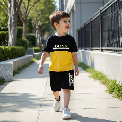 Child wearing a black and yellow 'BOYS' t-shirt and shorts walking outdoors.